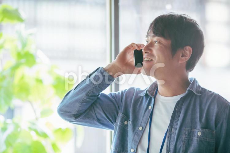 服装自由な会社でスマホを使う会社員 スマホ,スマートフォン,男性の写真素材