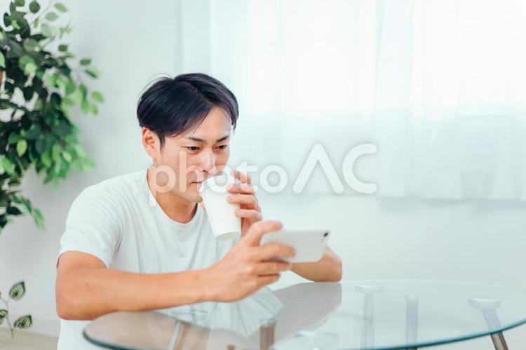 部屋でスマホを見る男性（微笑み） スマホ,スマートフォン,アプリの写真素材