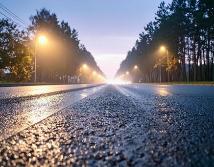薄暗い時間帯の街灯に照らされた道路 薄暗い時間帯の街灯に照らされた道路の写真