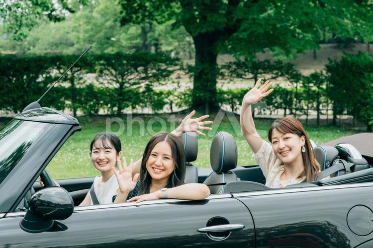 ドライブする女性たち（手を振る） 旅行,車,友達の写真素材