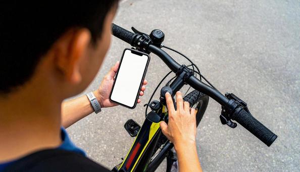 自転車を止めてスマホを見る男の子 自転車を止めてスマホを見る男の子の写真