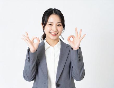 オーケーサインをするスーツ姿の女性の写真