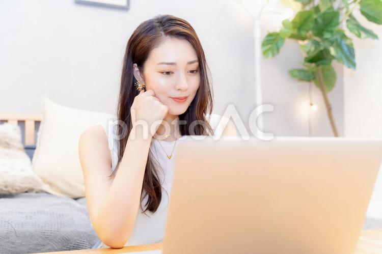 部屋でノートパソコンを使う笑顔の女性 女性,パソコン,ノートパソコンの写真素材