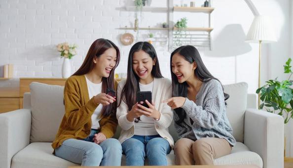 3人の若い女性が携帯を見ながら会話 3人の若い女性が携帯を見ながら会話の写真