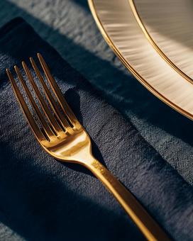 高級感ある食卓の金色のフォーク 高級感ある食卓の金色のフォークの写真