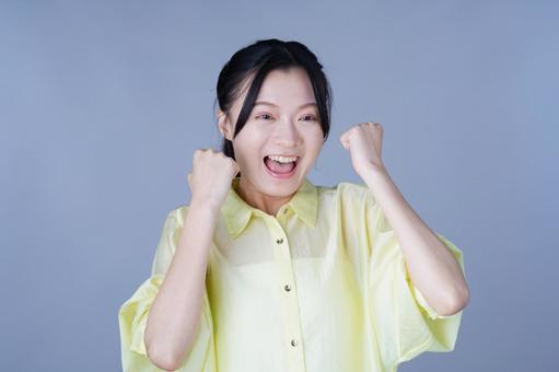 両手でガッツポーズ黄色い服の女性の写真