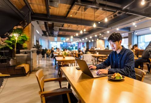 お洒落なカフェでパソコン作業する若い男性 お洒落なカフェでパソコン作業する若い男性の写真