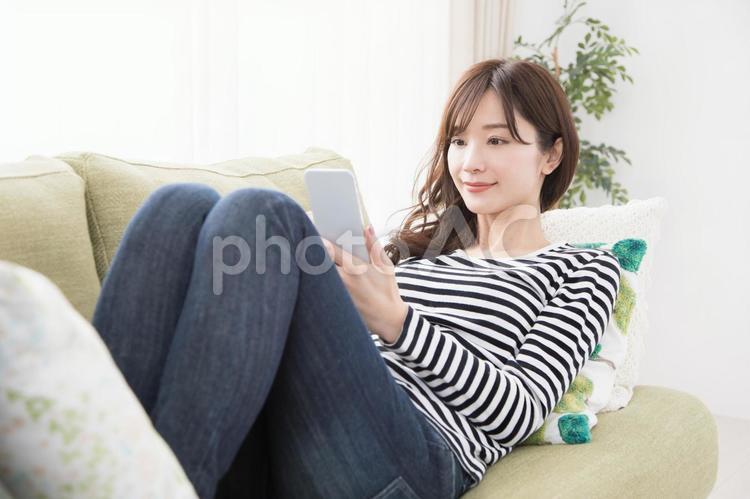 ソファーでスマホを使う女性 スマホ,女性,人物の写真素材
