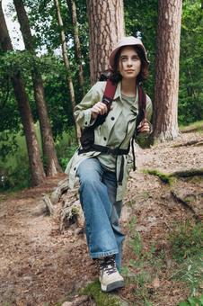 森の中でリュックを背負って立つ女性の写真