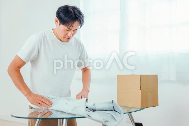 洋服を畳んで段ボールに入れる男性 フリマ,売る,不用品の写真素材