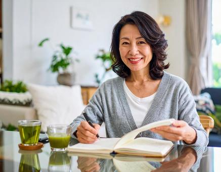 テキストを開きノートに書く日本人女性 テキストを開きノートに書く日本人女性の写真