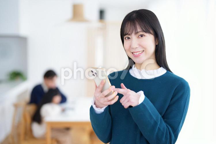 携帯を指さしてカメラ目線の女性 家族,女性,女の子の写真素材