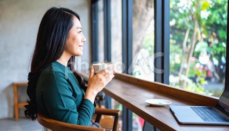 本とコーヒーカップを手にくつろぐ女性 カフェ,読書,自己啓発の写真素材