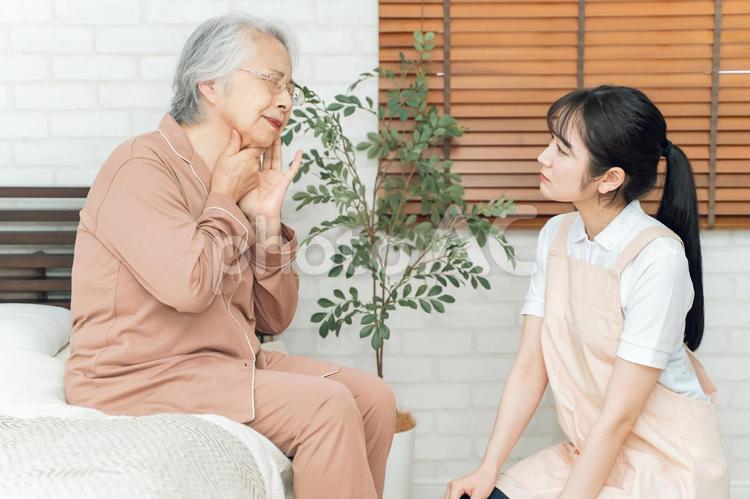 痛がる高齢者女性とエプロン姿の女性（のど） 高齢者,喉,のどの写真素材