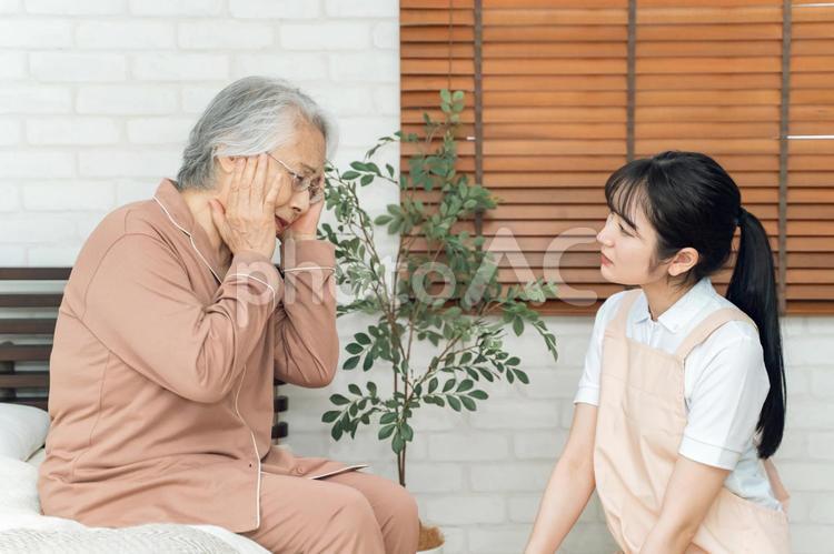 痛がる高齢者女性とエプロン姿の女性（頭痛） 高齢者,頭痛,脳の写真素材