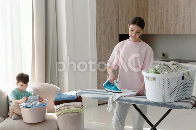 ソファーに座って畳む男の子とアイロンをする女性 親子,女性,人物の写真素材