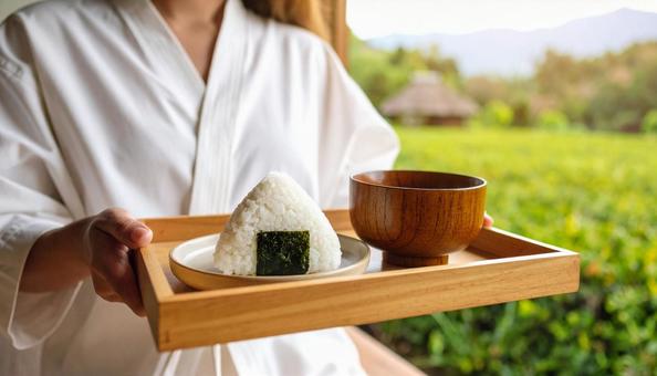 お盆に乗ったおにぎりと味噌汁を持つ女性 お盆に乗ったおにぎりと味噌汁を持つ女性の写真
