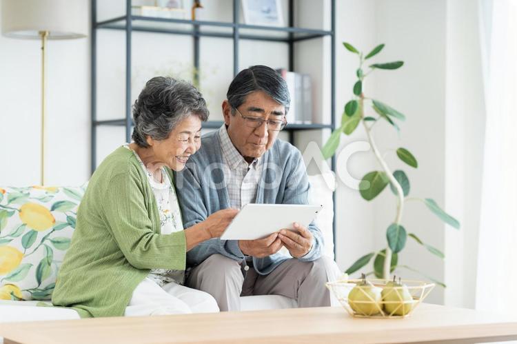 リビングでタブレットを見るシニアの夫婦 シニア,夫婦,タブレットの写真素材