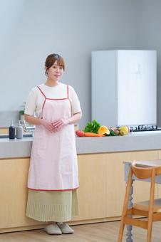 キッチンに立つエプロンの女性 女性,エプロン,野菜の写真素材