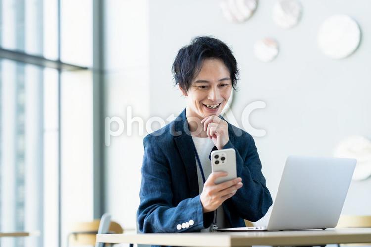 オフィスでスマホを見るビジネスマン スマートフォン,オフィス,エンジニアの写真素材