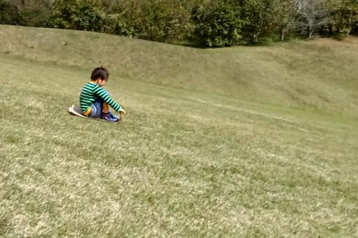 <素材>公園の芝生で草スキーをする少年 <素材>公園の芝生で草スキーをする少年の写真