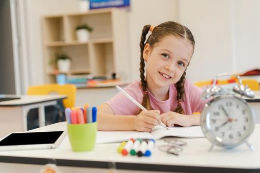 カメラ目線で時計を置いて勉強する女の子 女の子,子ども,人物の写真素材