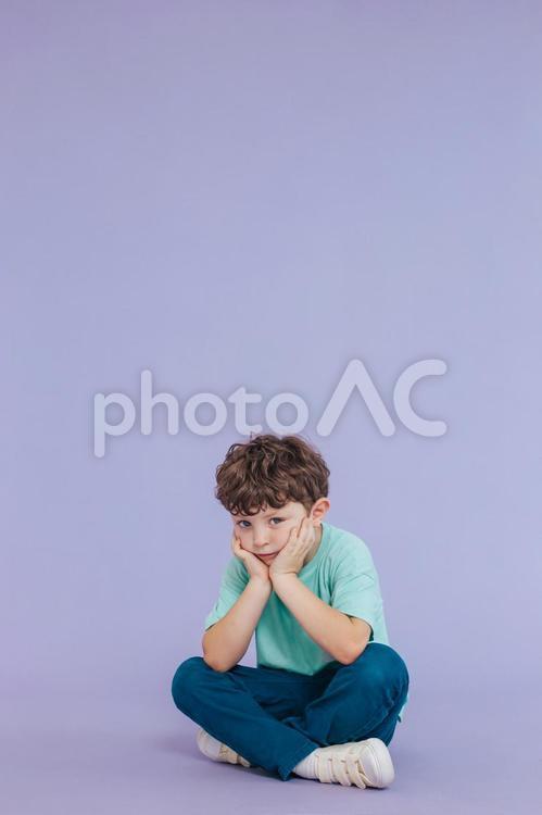 カメラ目線で頬杖をしてしゃがむ男の子 男の子,座る,胡坐の写真素材