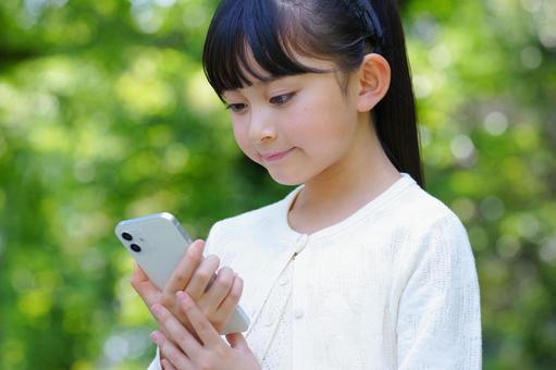 公園でスマートフォンを使う女の子 子ども,女の子,小学生の写真素材