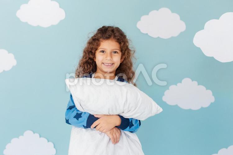 枕を持ちカメラ目線の女の子 女の子,笑顔,パジャマの写真素材