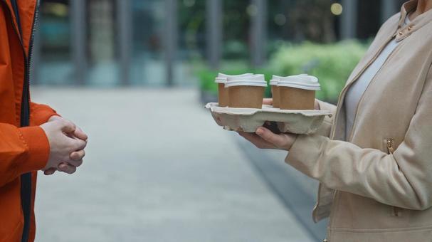 コーヒーを届けたフードデリバリーの男性と受け取る女性の手元 配達,フードデリバリー,デリバリーの写真素材