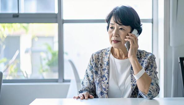 困った表情で電話する高齢者の写真