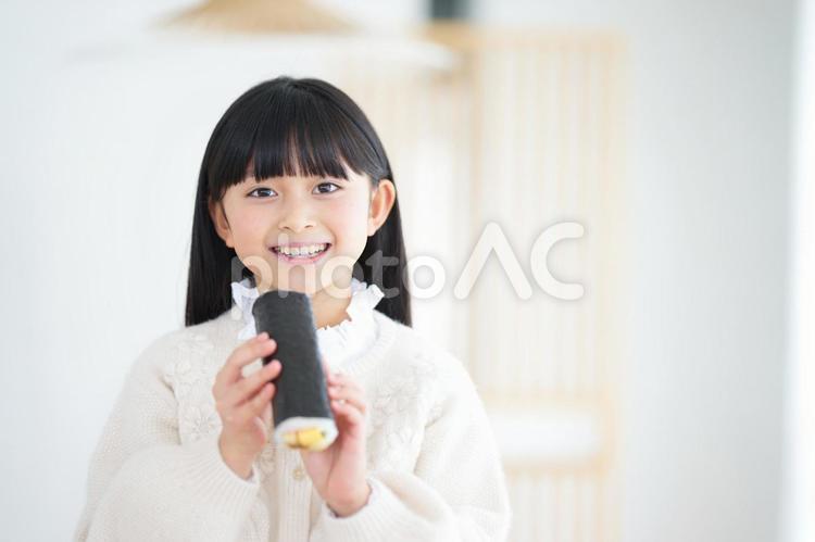 カメラ目線で太巻きを持っている女の子 女の子,ロングヘア,長袖の写真素材