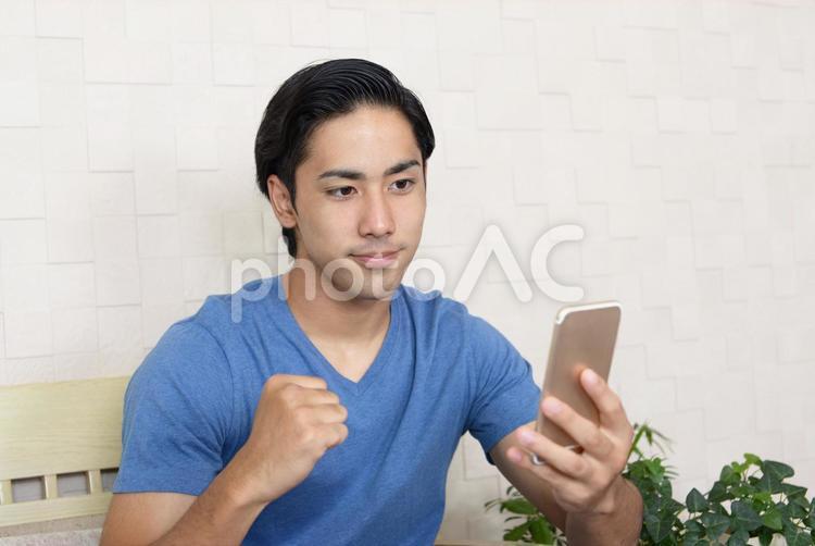 スマートフォンを持つ男性　ガッツポーズ スマホ,スマートフォン,アイフォンの写真素材