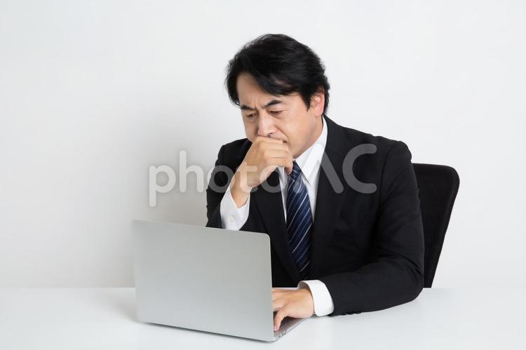 悩みながら仕事をしている中年のサラリーマン男性 中年,上司,会社員の写真素材