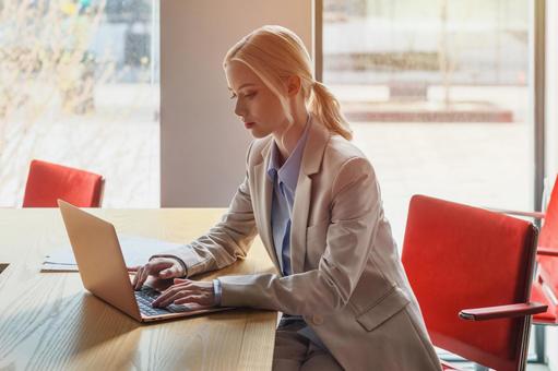 窓のあるオフィスでノートパソコンを使っているビジネスウーマン ビジネスウーマン,ビジネス,女性の写真素材