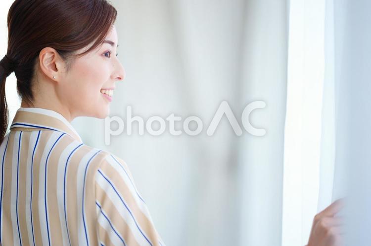 レースのカーテンを開けて遠くをも見る女性の横顔 キャリアウーマン,女性,窓の写真素材