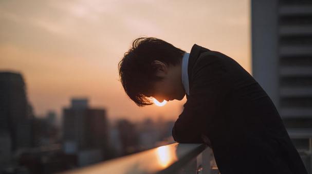 ビルの屋上で悩む男性 ビルの屋上で悩む男性の写真