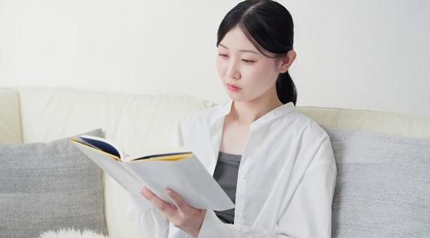 自宅で読書をするアジア人女性 自宅で読書をするアジア人女性 女性,読書,リビングの写真素材