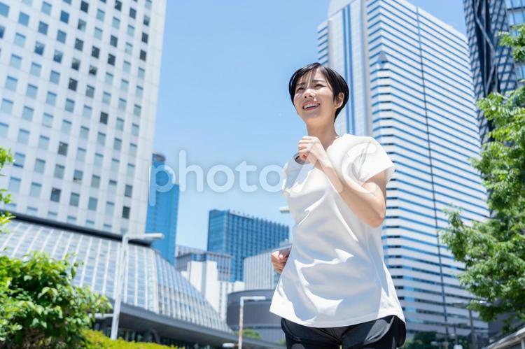 オフィス街をジョギングする若い女性 ランニング,ジョギング,フィットネスの写真素材