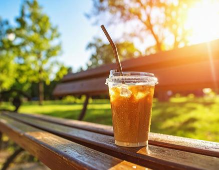 公園のベンチの上のカップのアイスコーヒー 公園のベンチの上のカップのアイスコーヒーの写真