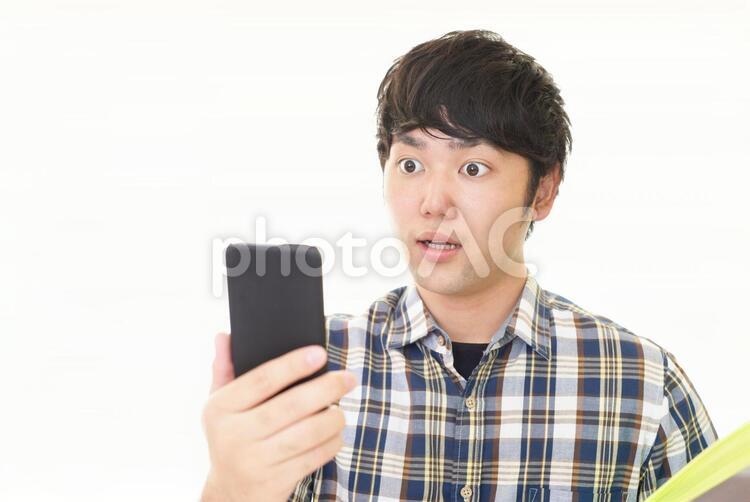 驚いた表情の男性 男性,男,スマートフォンの写真素材