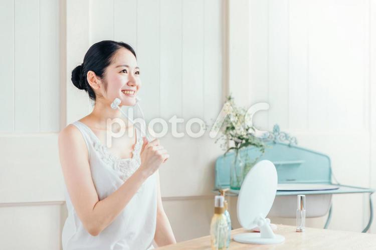 美顔ローラーを使う女性(笑顔) 美顔ローラーを使う女性(笑顔) 美顔ローラー,ローラー,顔痩せの写真素材