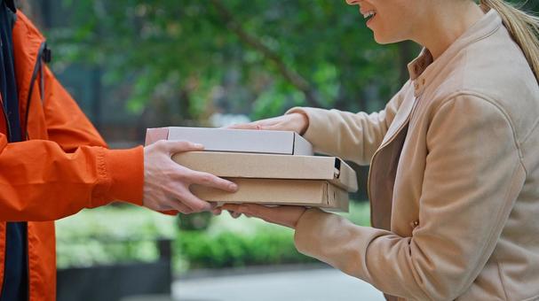 屋外で女性が配達員からピザを受け取っている 配達,フードデリバリー,デリバリーの写真素材