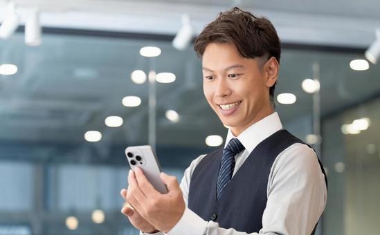 スマホを使う笑顔の男性ビジネスマン スマホを使う笑顔の男性ビジネスマン 男性,スマホ,スマートフォンの写真素材