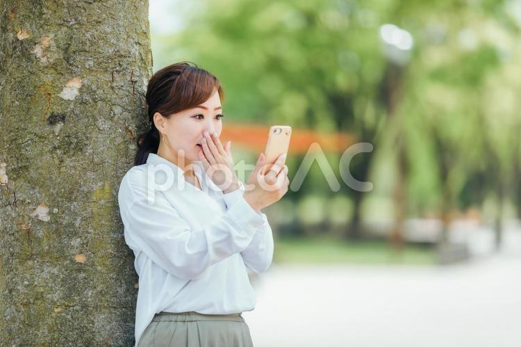 スマホを見て喜ぶビジネスウーマン スマホ,驚く,スマートフォンの写真素材