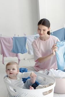 洗濯しながら赤ちゃんを見つめる女性 洗濯しながら赤ちゃんを見つめる女性 親子,女性,人物の写真素材