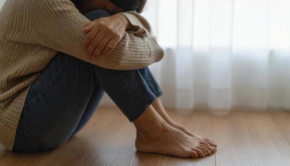 部屋で落ち込んで座る日本人女性の横顔の写真