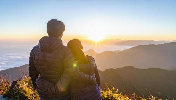 山から朝日を眺める日本人カップル 山から朝日を眺める日本人カップルの写真