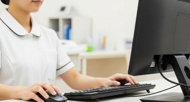 パソコンで確認をするアジア人看護師の手元 パソコンで確認をするアジア人看護師の手元の写真