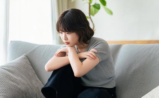 リビングのソファに座って考える女性 リビングのソファに座って考える女性 女性,考える,困るの写真素材